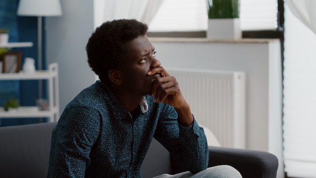 Portret van peinzende doordachte authentieke Afro-Amerikaanse man die uit het raam kijkt