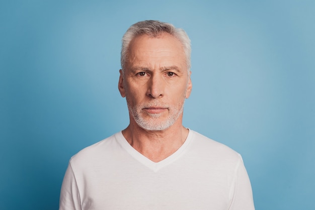 Portret van peinzende ernstige met witte haren oude man geïsoleerd op blauwe achtergrond