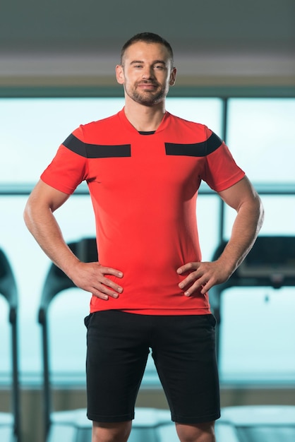 Portret van personal trainer in sportoutfit in fitnesscentrum sportschool staande sterk