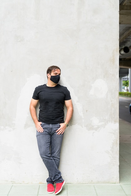 Portret van perzische man met masker voor bescherming tegen uitbraak van coronavirus op betonnen muur