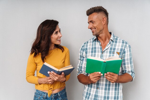 Portret van positief optimistisch gelukkig lachend volwassen verliefde paar geïsoleerd over grijze muur leesboek.