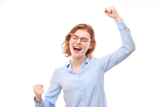 Portret van positief roodharig meisje in zakelijk overhemd verheugt zich emotioneel en voelt zich gelukkig geïsoleerd op een witte achtergrond reclamebanner