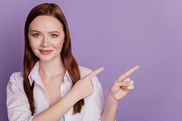 Portret van positieve adviseur dame directe vinger lege ruimte op violette achtergrond