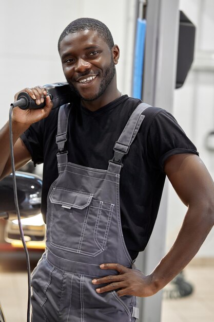 Portret van positieve afro amerikaanse automonteur in uniform poseren na het werk