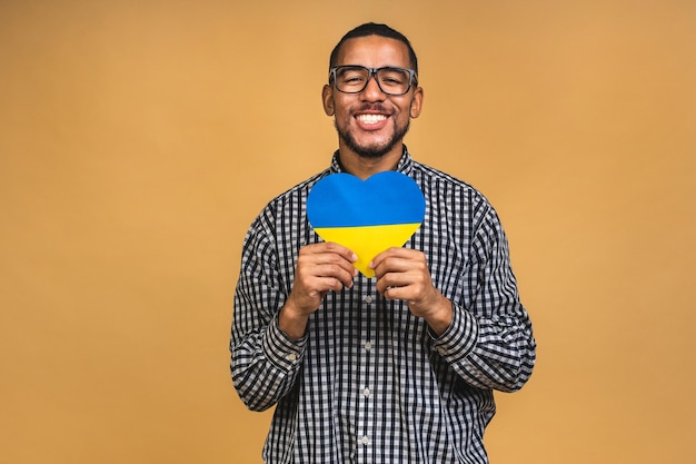 Portret van positieve afro-amerikaanse zwarte man met oekraïense vlag geïsoleerd over beige achtergrond