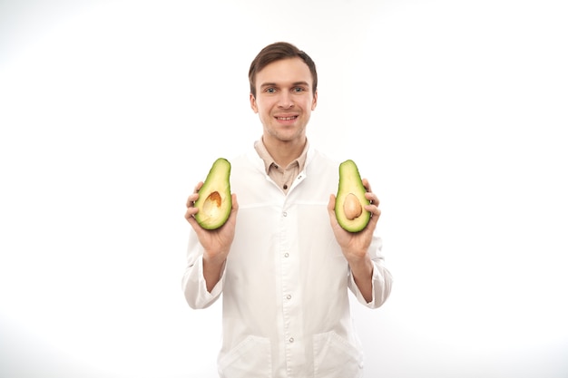 Portret van positieve glimlachende mannelijke voedingsdeskundige arts met avocado.