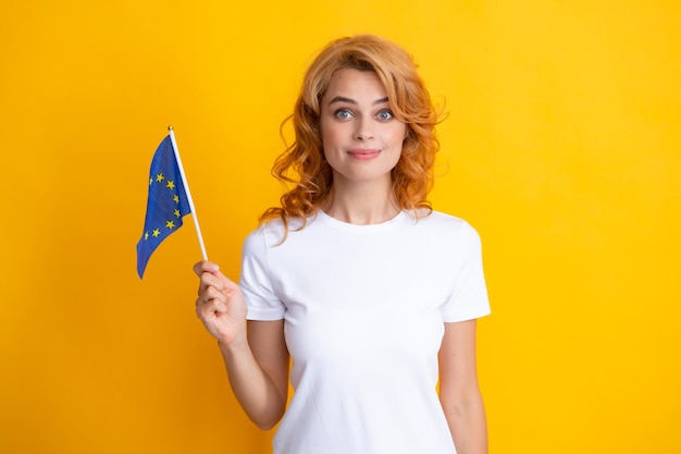 Portret van positieve student vrouw met de vlag van de europese unie geïsoleerd op gele achtergrond eu-vereniging gelukkig meisje met de vlag van de immigratie van de europese unie en reizen in europa