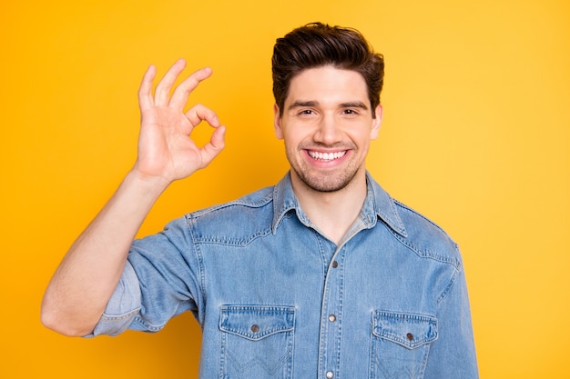 Portret van positieve vrolijke kerel promotor toon goed teken adviseren promo-advertenties dragen casual stijl kleding geïsoleerd over gele kleur muur