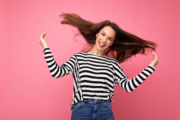 Portret van positieve vrolijke modieuze vrouw in casual kleding geïsoleerd op roze achtergrond met