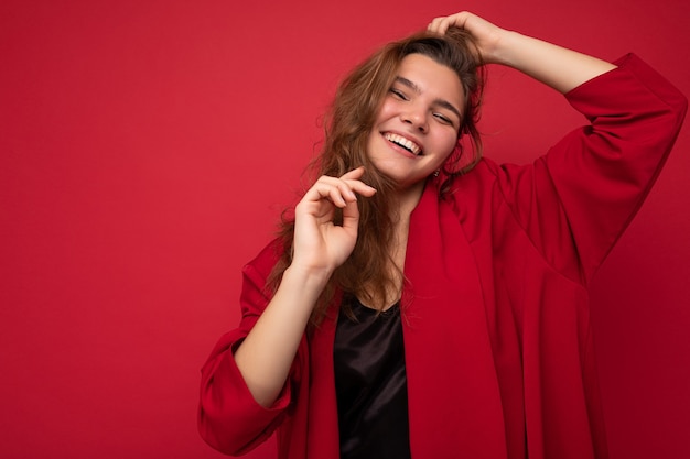 Portret van positieve vrolijke modieuze vrouw in formalwear kijken camera geïsoleerd op rood