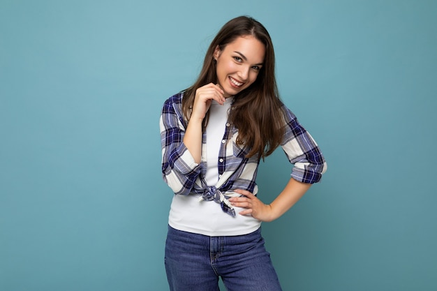 Portret van positieve vrolijke modieuze vrouw in hipster outfit geïsoleerd op blauwe achtergrond met kopie ruimte.