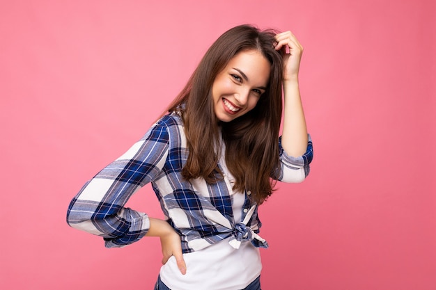 Portret van positieve vrolijke modieuze vrouw in hipsteruitrusting die op roze wordt geïsoleerd