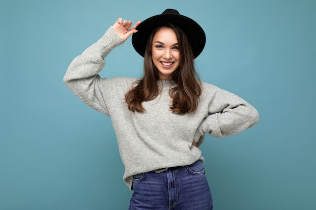 Portret van positieve vrolijke modieuze vrouw in stijlvolle kleding geïsoleerd op blauwe achtergrond met