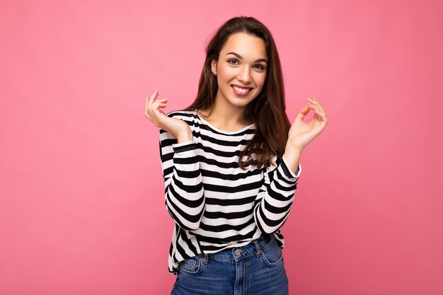 Portret van positieve vrolijke modieuze vrouw in vrijetijdskleding die op roze wordt geïsoleerd