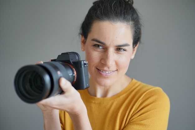 Portret van prachtige brunette fotograaf op grijs