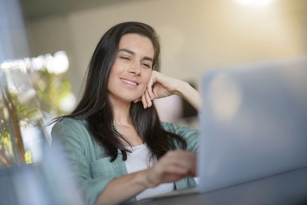 Portret van prachtige brunette lachend op haar laptop