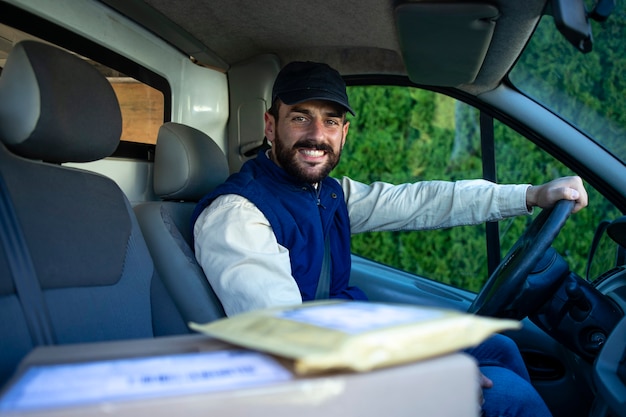 Portret van professionele bezorger die zijn busje met pakketten bestuurt.