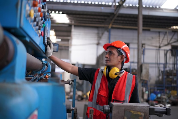 Portret van professionele ingenieur/werknemer in de zware industrie die veiligheidsuniform, veiligheidsbril en veiligheidshelm draagt. op de achtergrond ongericht grote industriële fabriek