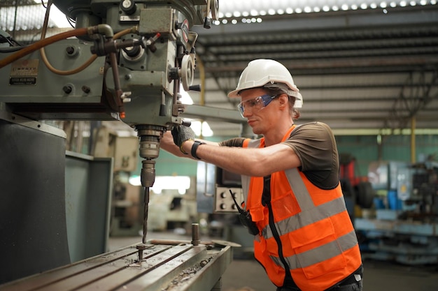 Portret van professionele ingenieur/werknemer in de zware industrie die veiligheidsuniform, veiligheidsbril en veiligheidshelm draagt. Op de achtergrond ongericht grote industriële fabriek