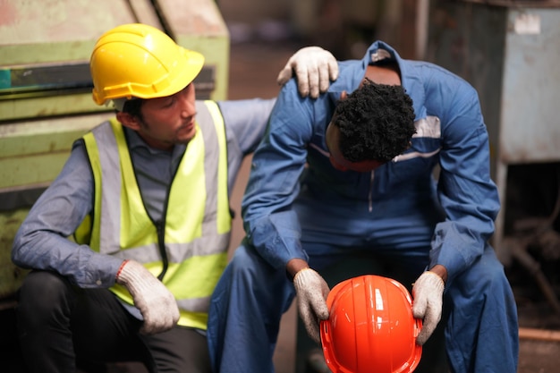 Portret van professionele ingenieur/werknemer in de zware industrie die veiligheidsuniform, veiligheidsbril en veiligheidshelm draagt. Op de achtergrond ongericht grote industriële fabriek