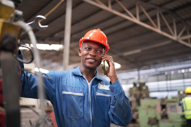 Portret van professionele ingenieur/werknemer in de zware industrie die veiligheidsuniform, veiligheidsbril en veiligheidshelm draagt. Op de achtergrond ongericht grote industriële fabriek