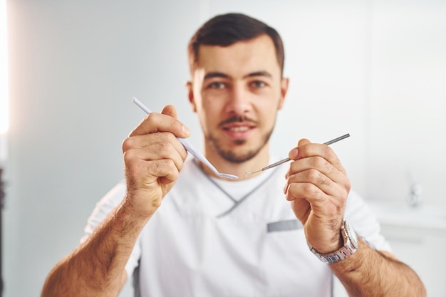 Portret van professionele tandarts met apparatuur die binnenshuis staat