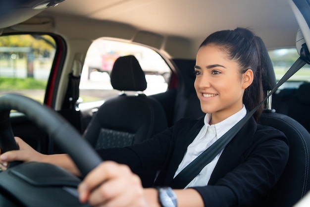 Portret van professionele vrouwelijke chauffeur die haar auto bestuurt. vervoersconcept.