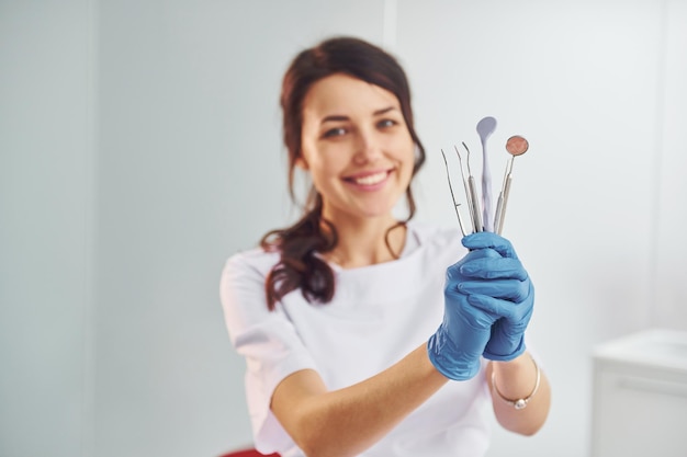 Portret van professionele vrouwelijke tandarts met apparatuur die binnenshuis staat