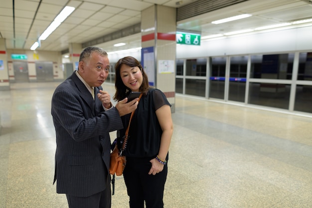 Portret van rijpe Japanse zakenman en rijpe Japanse vrouw die de stad Bangkok verkennen