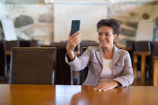 Portret van rijpe mooie onderneemster bij de koffiewinkel