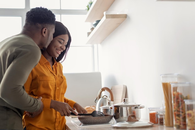 Portret van romantisch jong Afrikaans Amerikaans paar dat samen in keuken kookt