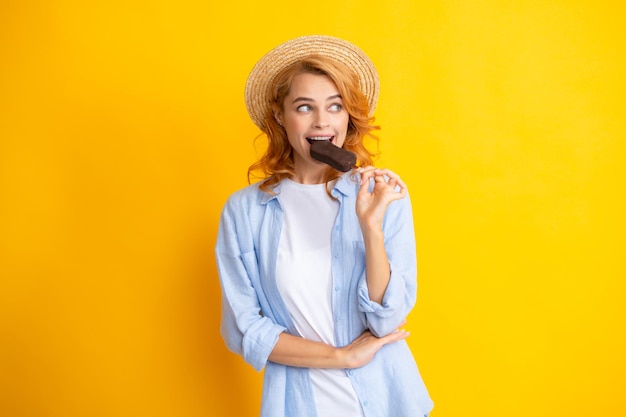 Portret van roodharig meisje met chocolade-ijs op gele achtergrond Krullende vrolijke vrouw aan het eten