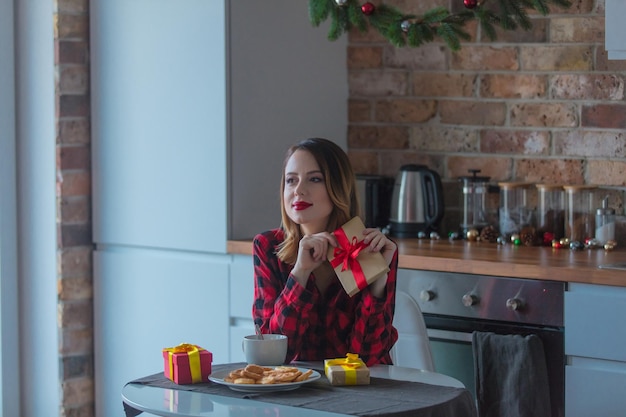 Portret van roodharige vrouw met kopje koffie of thee in de keuken in de kersttijd