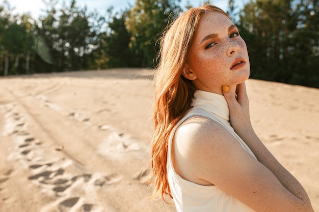 portret van rustige roodharige vrouw met lang golvend haar teder nek aanraken