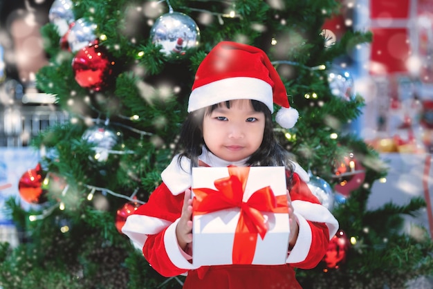 Portret van schattig Aziatisch meisje draagt kerstjurk gelukkig in de buurt van kerstboom Thailand kind sluit zich aan bij kerstfestival