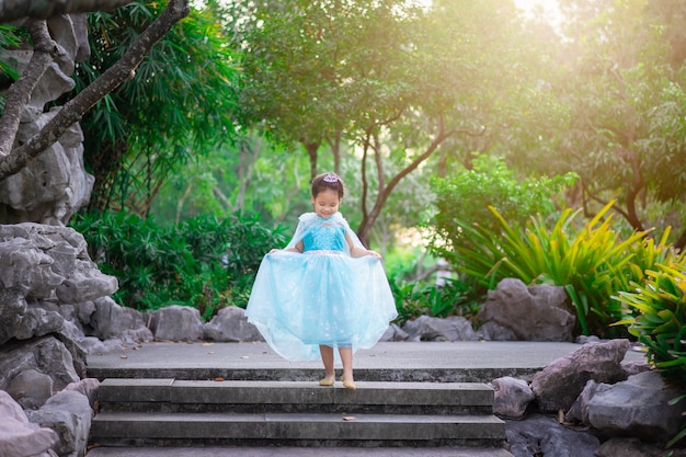 Portret van schattig glimlachend meisje in prinses kostuum lopen de trap af in het park