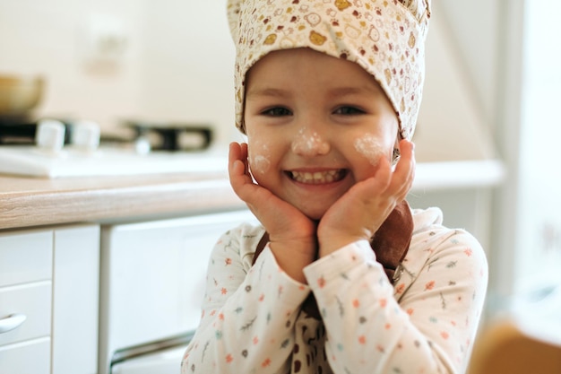 Portret van schattig klein homecook-meisje in witte keuken