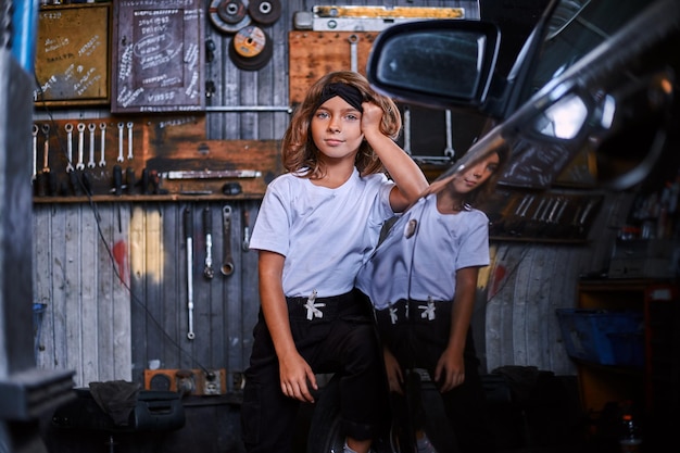 Portret van schattig klein meisje in de buurt van glanzende auto bij atuo service workshop.