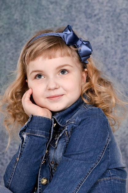 Portret van schattig klein meisje in jeans jasje poseren in studio