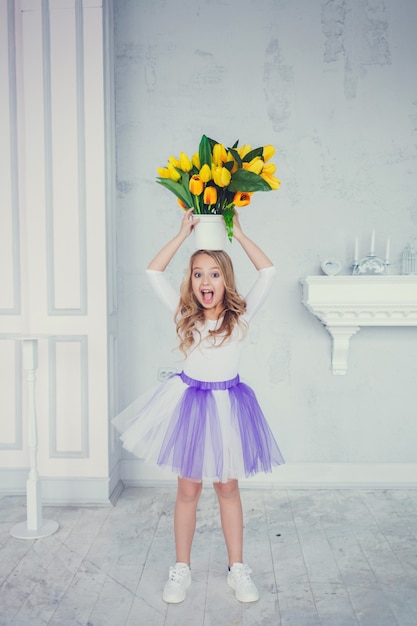 Portret van schattig klein meisje in rok met gele tulpen bloem