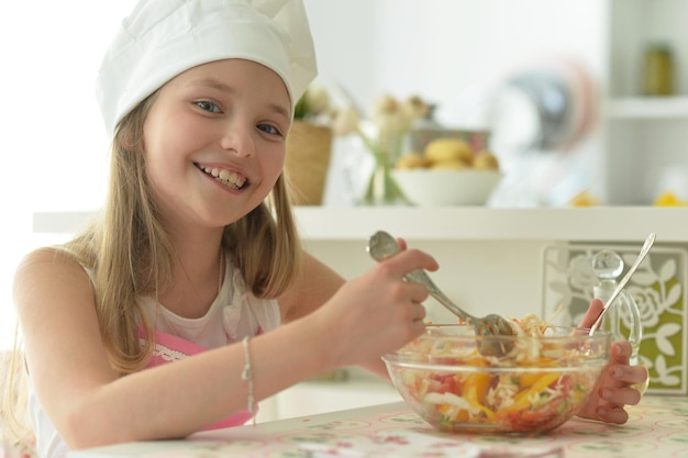 Portret van schattig meisje dat salade eet in de keuken