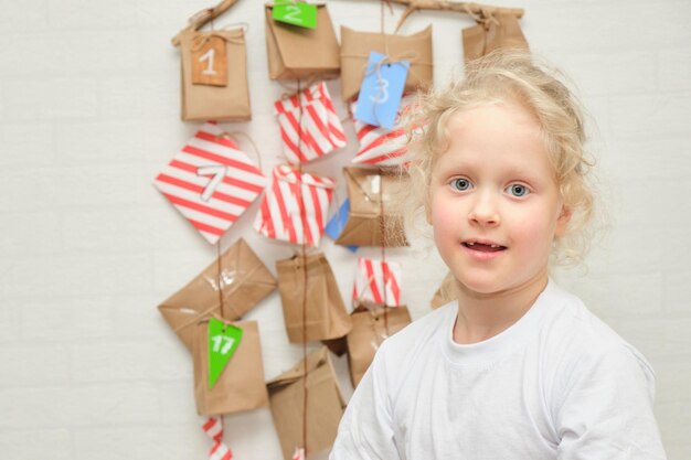 Portret van schattig meisje met verloren melktanden speelt met een anventkalender die aan de muur hangt