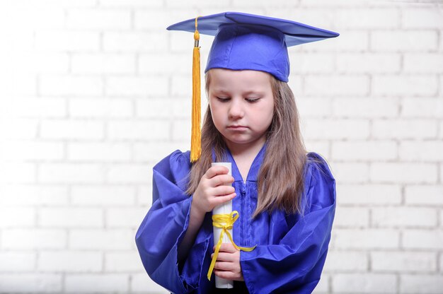 Portret van schattig schoolmeisje met afstuderen hoed in de klas