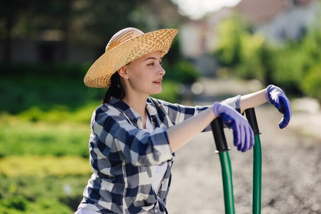 Portret van schattig tuinmanmeisje met kruiwagen die in tuinmarkt werken.