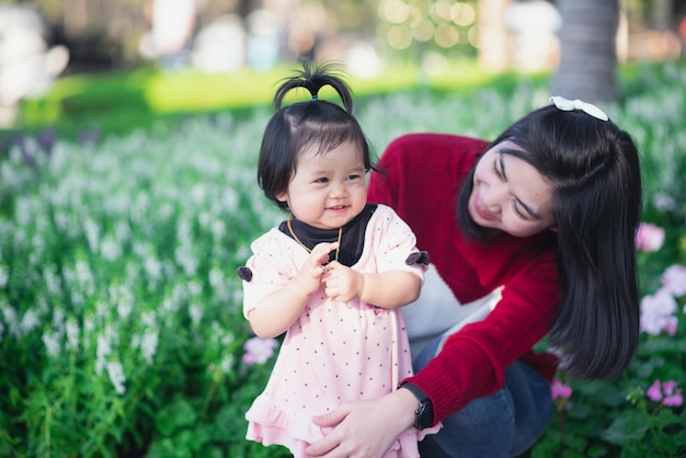 Portret van schattige baby en haar moeder reizen op bloementuin