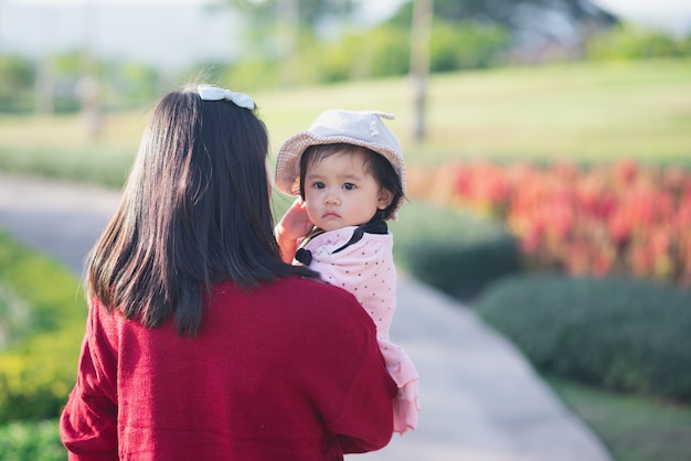 Foto portret van schattige baby en haar moeder reizen op bloementuin