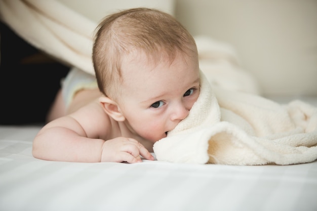 Portret van schattige baby van 6 maanden liggend op witte lakens