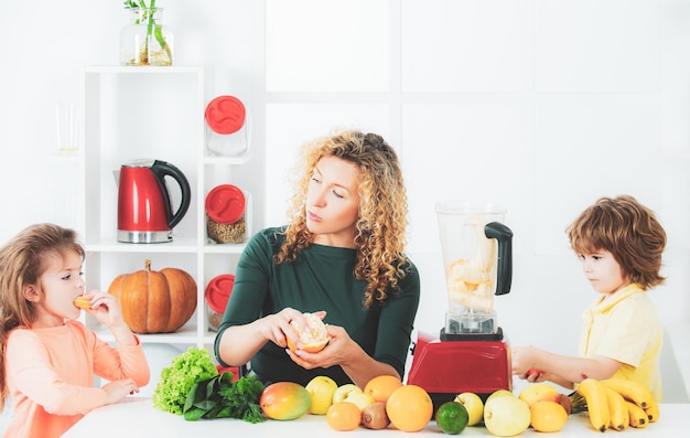 Portret van schattige familie maakt thuis vruchtensap op witte keuken gezond voedsel