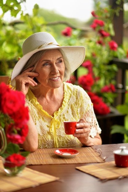 Portret van schattige gelukkige bejaarde vrouw die koffie drinkt