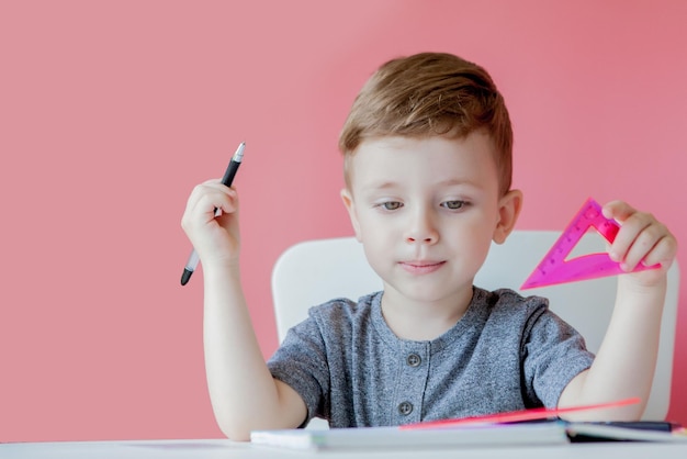 Portret van schattige jongen die thuis huiswerk maakt Geconcentreerd kind schrijven met kleurrijk potlood binnenshuis Basisschool en onderwijs Kind leren schrijven van letters en cijfers
